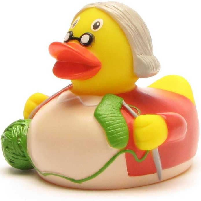 Pato de goma abuela tejiendo calcetines con ovillos de lana
